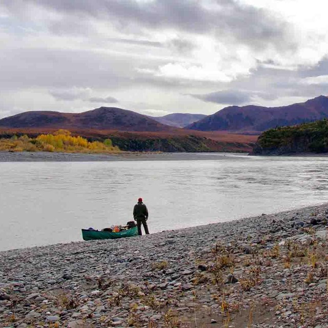 A boat pulls onto the shore of a wild Arctic river.